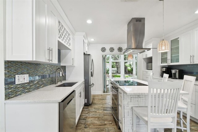 kitchen featuring a kitchen island, appliances with stainless steel finishes, ornamental molding, island exhaust hood, and a sink