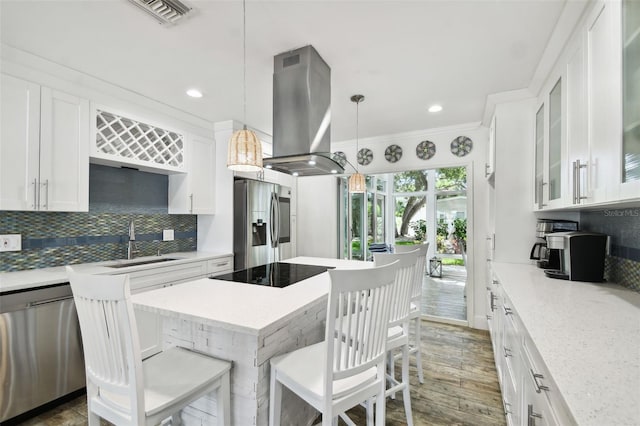 kitchen featuring visible vents, decorative backsplash, island exhaust hood, stainless steel appliances, and a sink