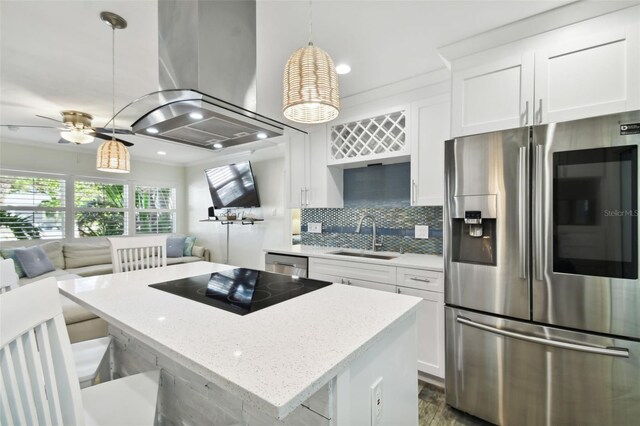 kitchen featuring a sink, open floor plan, appliances with stainless steel finishes, a center island, and tasteful backsplash