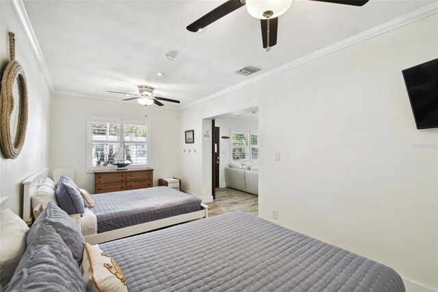 bedroom featuring ornamental molding, visible vents, light wood finished floors, and multiple windows