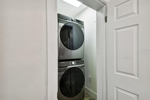 laundry area featuring laundry area, stacked washer / drying machine, and a textured wall