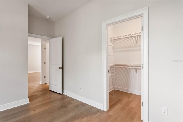 unfurnished bedroom with a spacious closet, hardwood / wood-style floors, and a closet