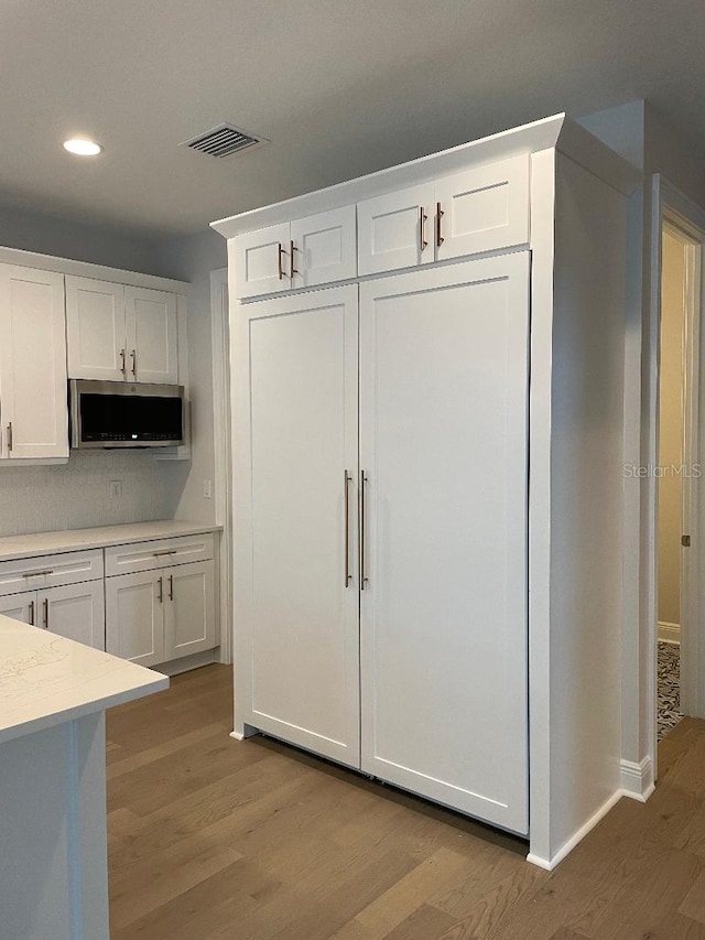 kitchen with white cabinetry, light hardwood / wood-style flooring, and tasteful backsplash