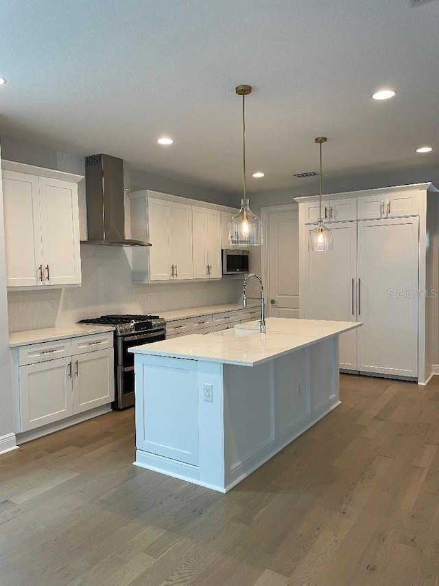 kitchen with pendant lighting, white cabinets, stainless steel appliances, and wall chimney exhaust hood