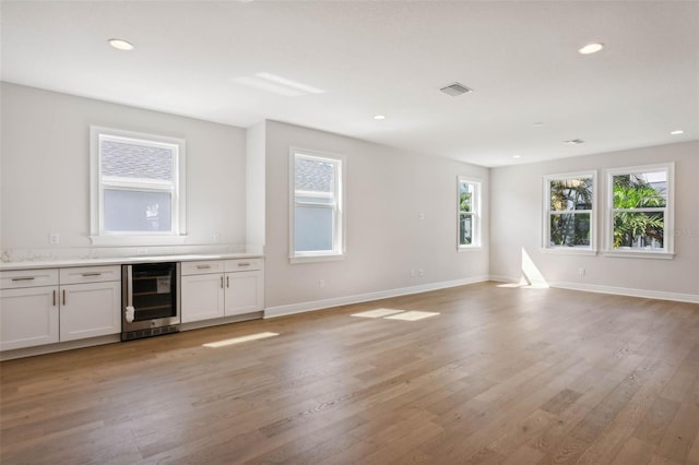 bar featuring wine cooler, white cabinetry, light hardwood / wood-style floors, and a healthy amount of sunlight