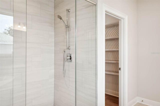 bathroom featuring wood-type flooring and a tile shower