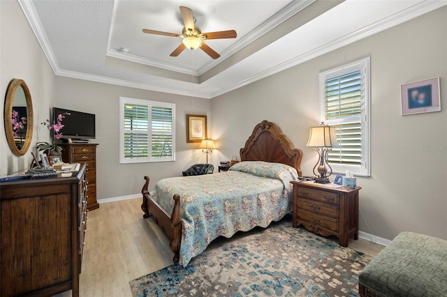 bedroom featuring ceiling fan, ornamental molding, a tray ceiling, and light hardwood / wood-style floors