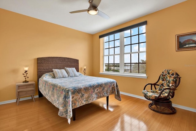 bedroom with hardwood / wood-style floors, ceiling fan, and multiple windows