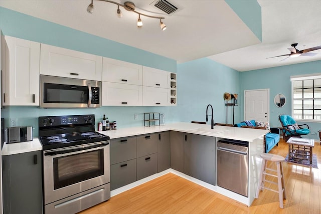 kitchen with kitchen peninsula, white cabinetry, sink, and appliances with stainless steel finishes