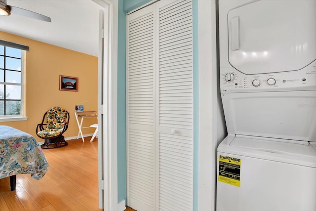 clothes washing area featuring hardwood / wood-style floors and stacked washer and dryer