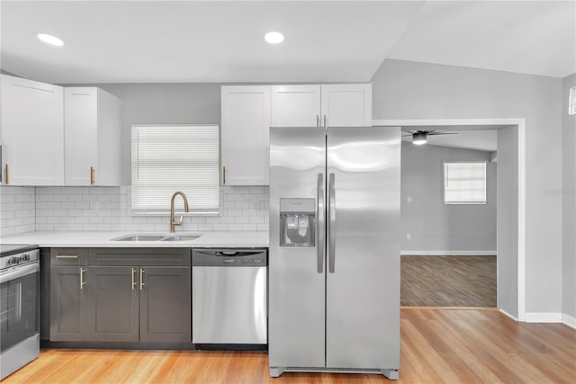 kitchen with white cabinets, sink, light hardwood / wood-style flooring, vaulted ceiling, and stainless steel appliances