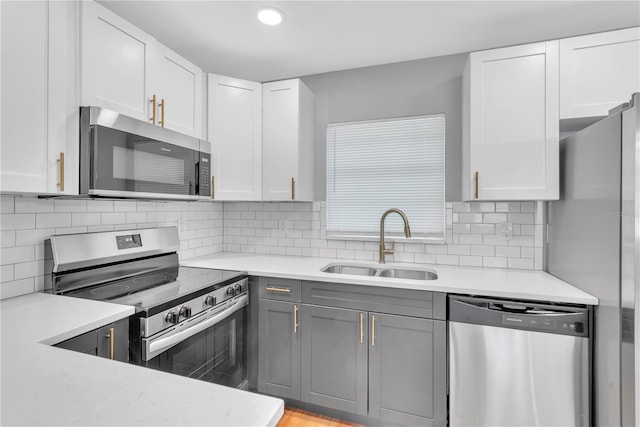 kitchen with tasteful backsplash, sink, white cabinets, and stainless steel appliances