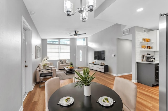 dining room featuring ceiling fan with notable chandelier and light hardwood / wood-style floors