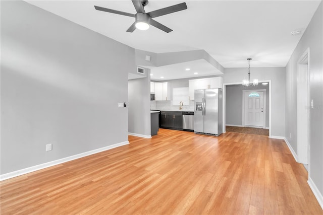 unfurnished living room featuring vaulted ceiling, sink, ceiling fan with notable chandelier, and light wood-type flooring