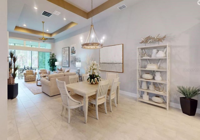 dining space with a chandelier and a raised ceiling