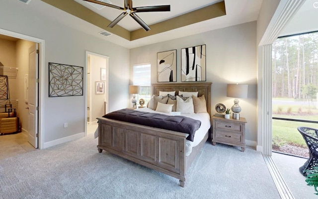 carpeted bedroom with access to exterior, ceiling fan, a tray ceiling, and connected bathroom