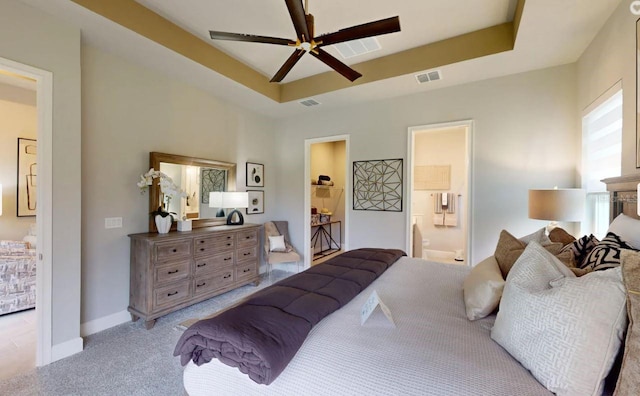 carpeted bedroom with ceiling fan, a raised ceiling, and connected bathroom