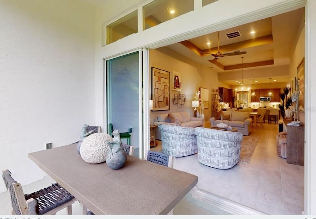 tiled living room with a high ceiling, ceiling fan, and a tray ceiling