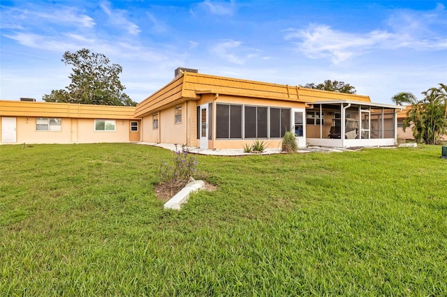 rear view of house with a yard and a sunroom