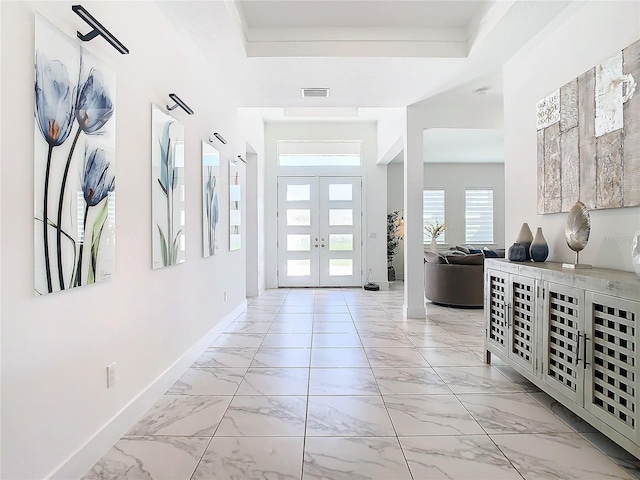 entryway with a raised ceiling and french doors