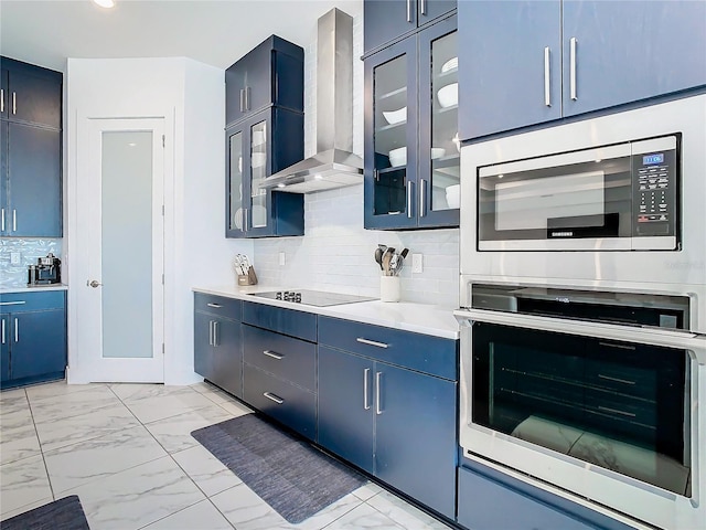 kitchen with stainless steel microwave, wall chimney exhaust hood, blue cabinetry, and black electric cooktop