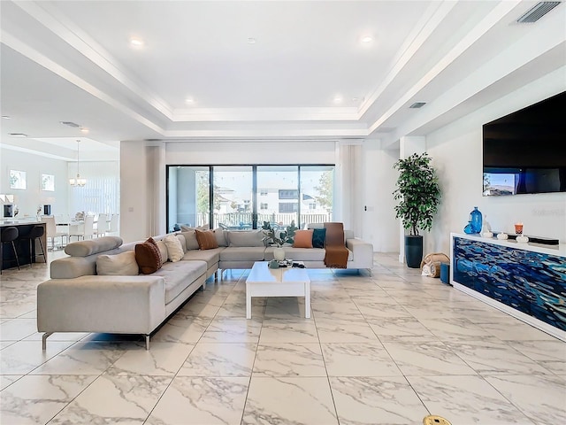 living room featuring a raised ceiling, a chandelier, and ornamental molding