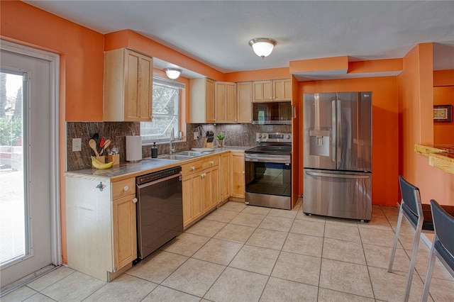 kitchen with decorative backsplash, light brown cabinetry, sink, and appliances with stainless steel finishes