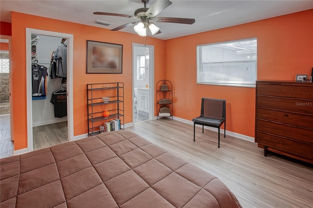 bedroom featuring a walk in closet, ceiling fan, connected bathroom, light hardwood / wood-style floors, and a closet