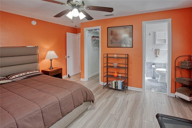 bedroom featuring a walk in closet, ceiling fan, light hardwood / wood-style flooring, connected bathroom, and a closet