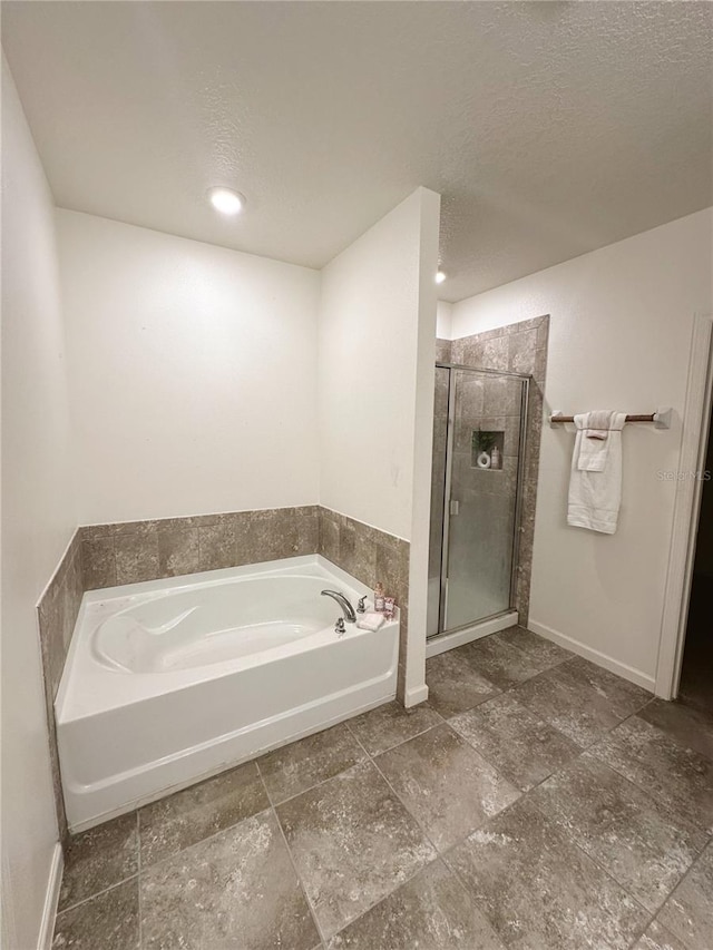 bathroom featuring a textured ceiling and plus walk in shower