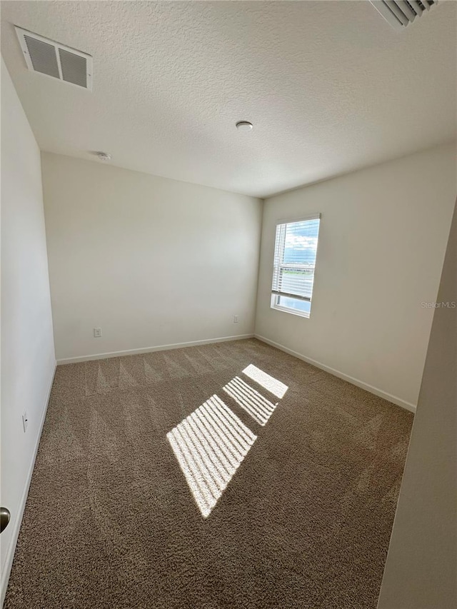 carpeted empty room with a textured ceiling