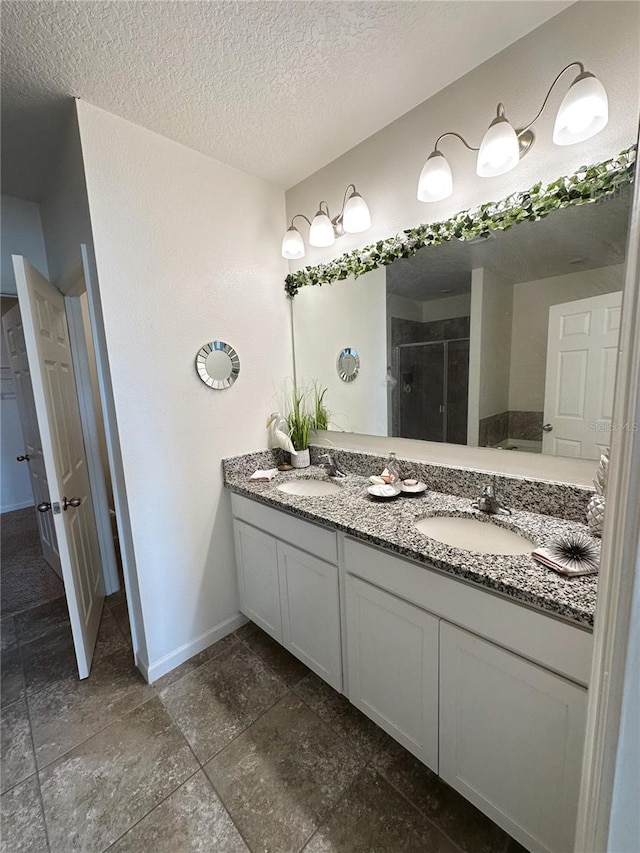 bathroom featuring a shower with door, vanity, and a textured ceiling