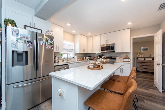 kitchen featuring dark hardwood / wood-style floors, white cabinetry, stainless steel appliances, and a kitchen island