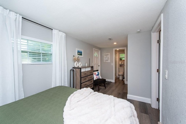 bedroom with dark wood-type flooring and ensuite bath