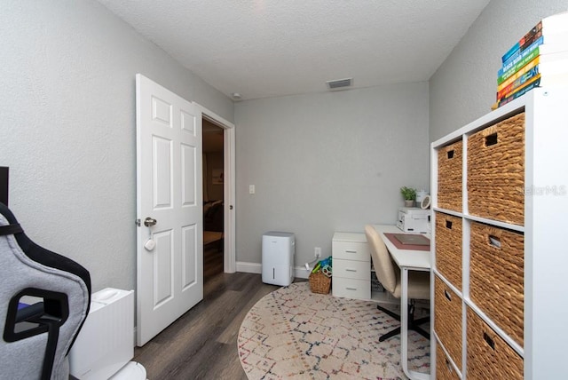 office with a textured ceiling and dark wood-type flooring