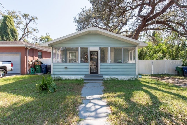 view of front of house featuring a sunroom, a front lawn, and a garage