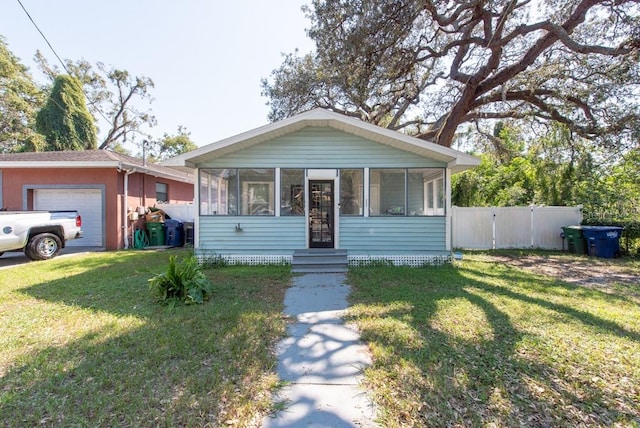 view of front of home with a front lawn, a garage, and a sunroom