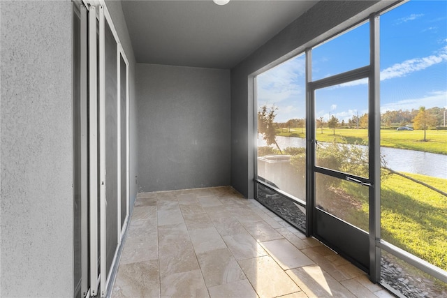 unfurnished sunroom featuring a water view