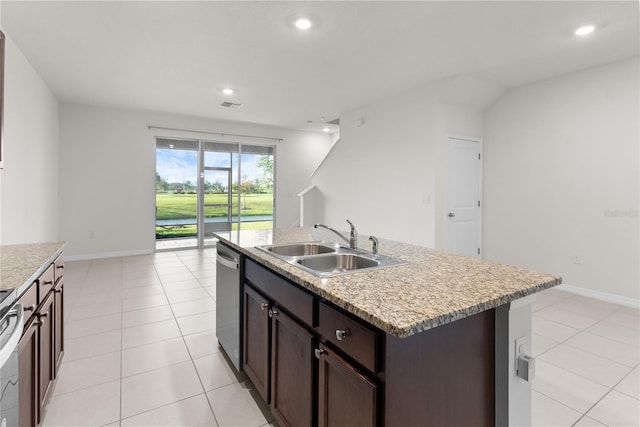 kitchen with a center island with sink, light tile patterned floors, stainless steel dishwasher, dark brown cabinetry, and sink