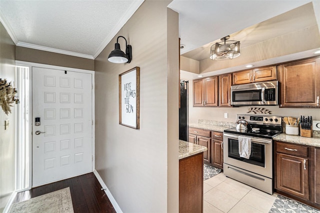 kitchen featuring a textured ceiling, light stone countertops, light hardwood / wood-style floors, crown molding, and stainless steel appliances