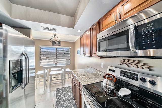 kitchen featuring light stone counters, stainless steel appliances, light tile patterned flooring, and crown molding