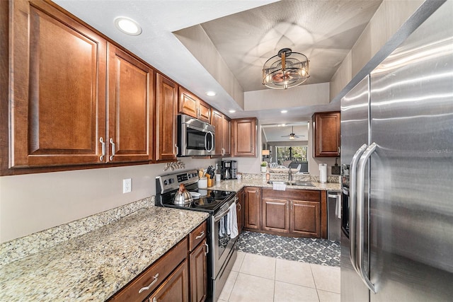 kitchen featuring light stone countertops, appliances with stainless steel finishes, ceiling fan, and light tile patterned floors