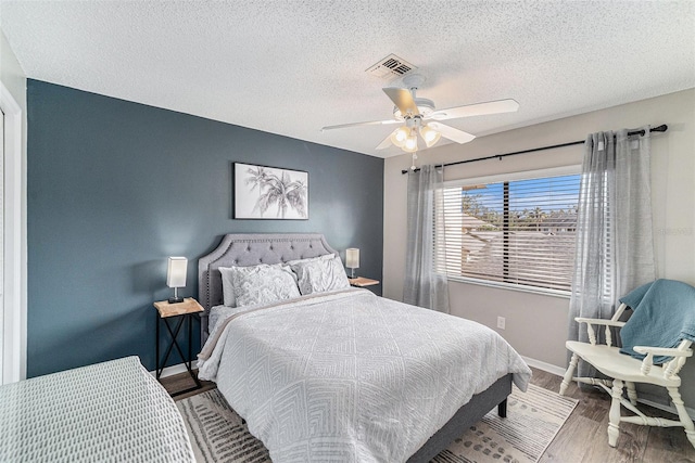 bedroom with a textured ceiling, hardwood / wood-style flooring, and ceiling fan