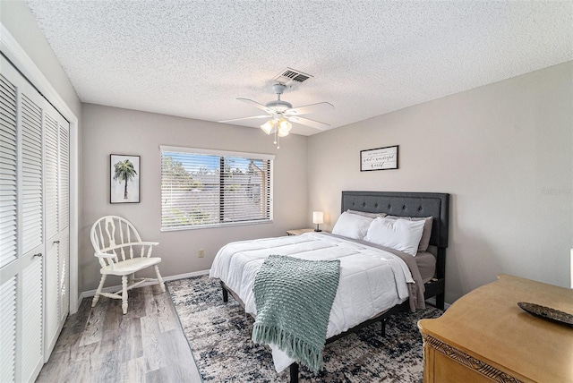 bedroom with hardwood / wood-style floors, a textured ceiling, a closet, and ceiling fan