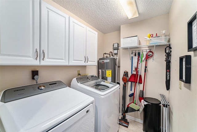 laundry area with washer and clothes dryer, water heater, light tile patterned floors, a textured ceiling, and cabinets