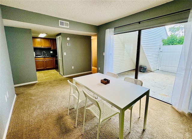 dining room featuring sink, light carpet, and a textured ceiling