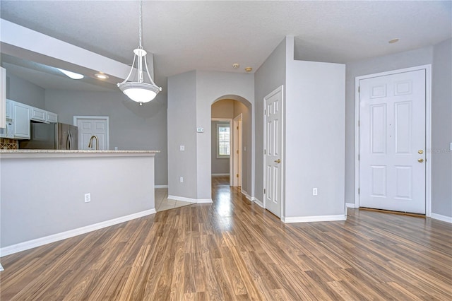 kitchen featuring a textured ceiling, pendant lighting, white cabinets, dark wood-type flooring, and stainless steel refrigerator