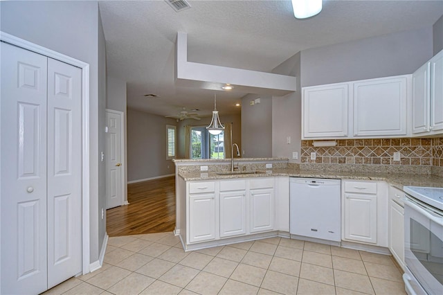 kitchen with white appliances, sink, a textured ceiling, kitchen peninsula, and white cabinets