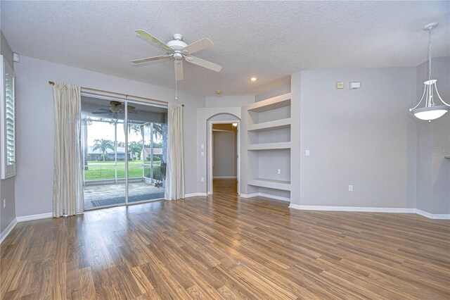 unfurnished living room featuring dark hardwood / wood-style floors, ceiling fan, a textured ceiling, and built in shelves