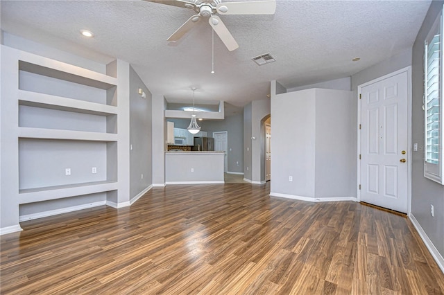 unfurnished living room featuring a textured ceiling, dark wood-type flooring, built in features, and ceiling fan